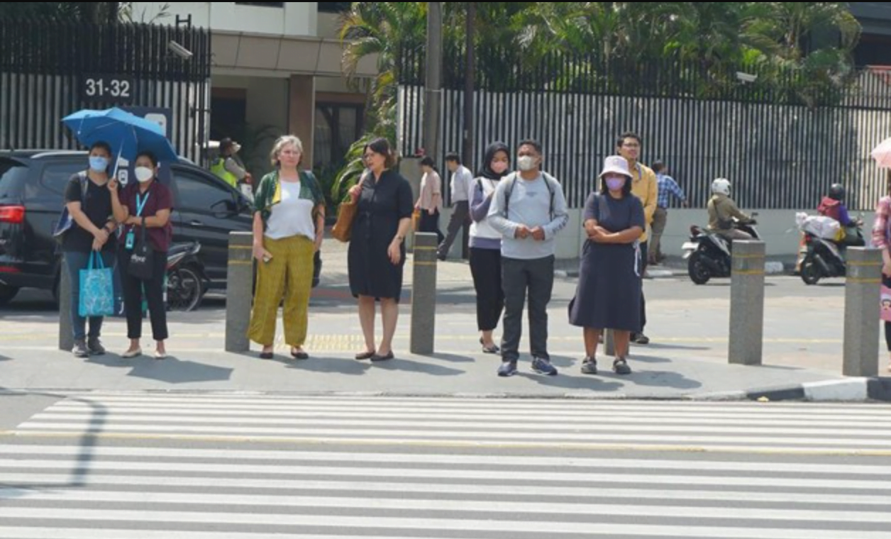 Foto: Pejalan kaki menggunakan payung untuk menghindari terik matahari di kawasan Jembatan Pinisi di halte busway Karet, Jakarta, Selasa (19/12/2023). (CNBC Indonesia/Muhammad Sabki)